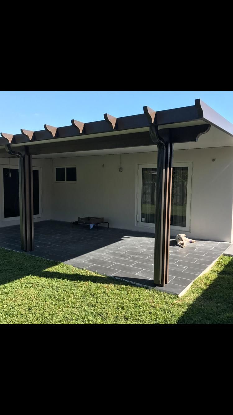 A white house with a covered patio in front of it.