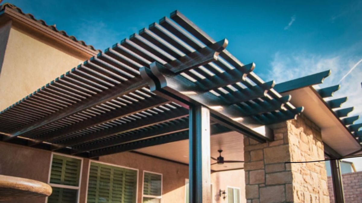 A pergola is sitting on top of a patio next to a house.