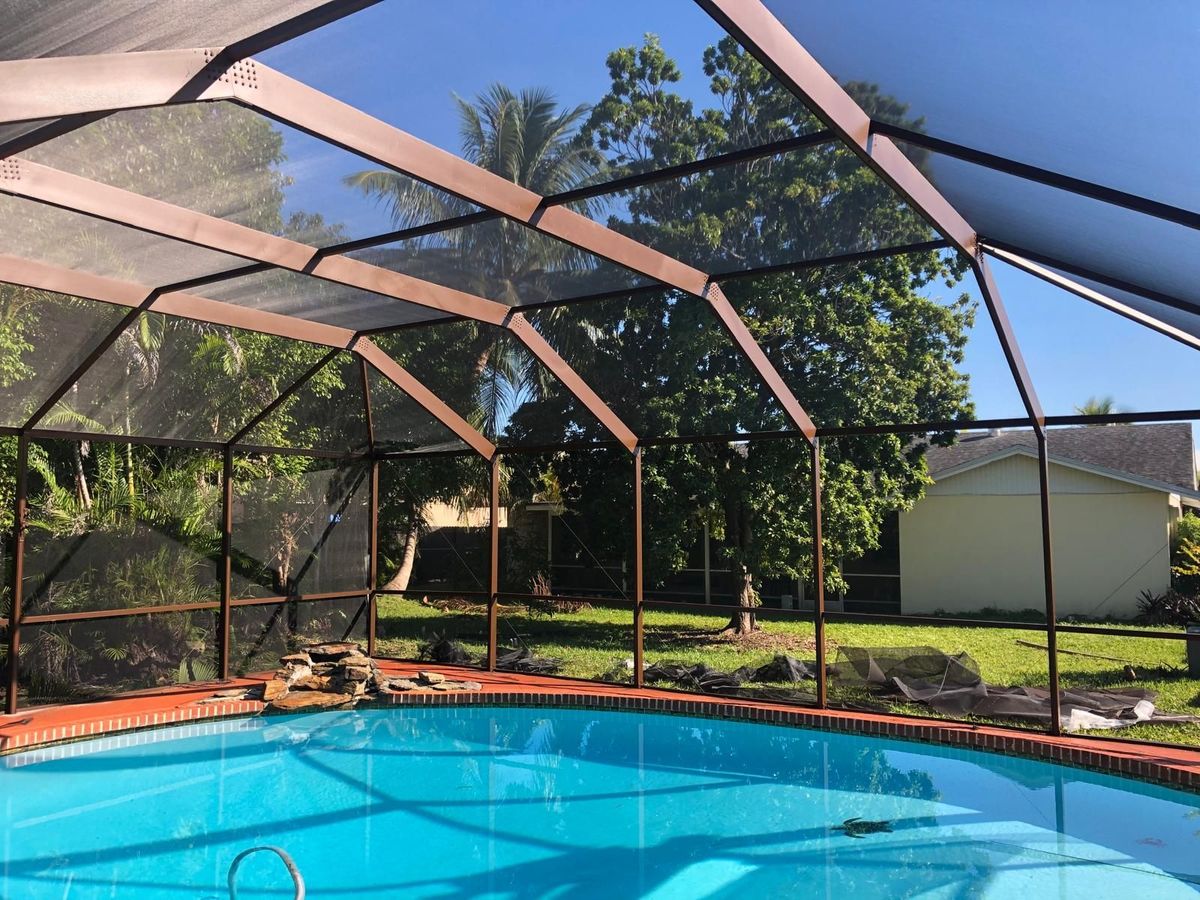 A screened in swimming pool with a house in the background