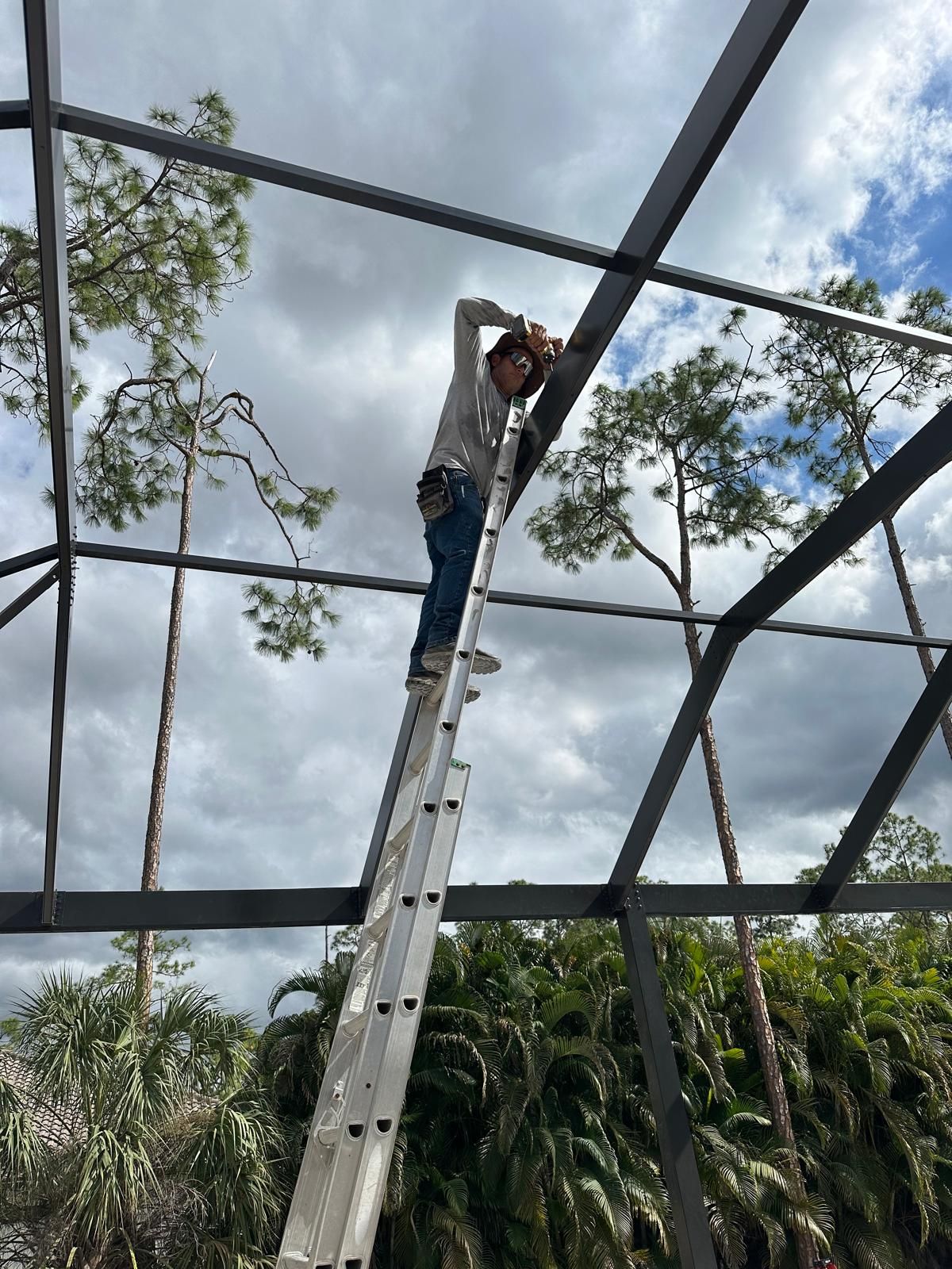 A man is standing on a ladder working on a metal structure.