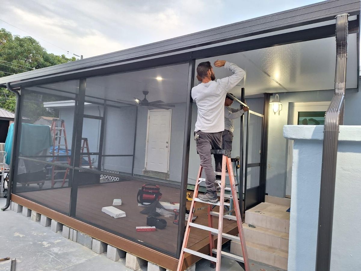 Two men are working on a screened in porch.