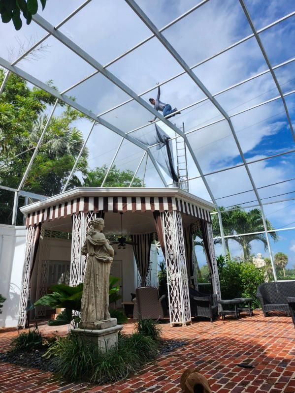 A man is cleaning the roof of a gazebo.