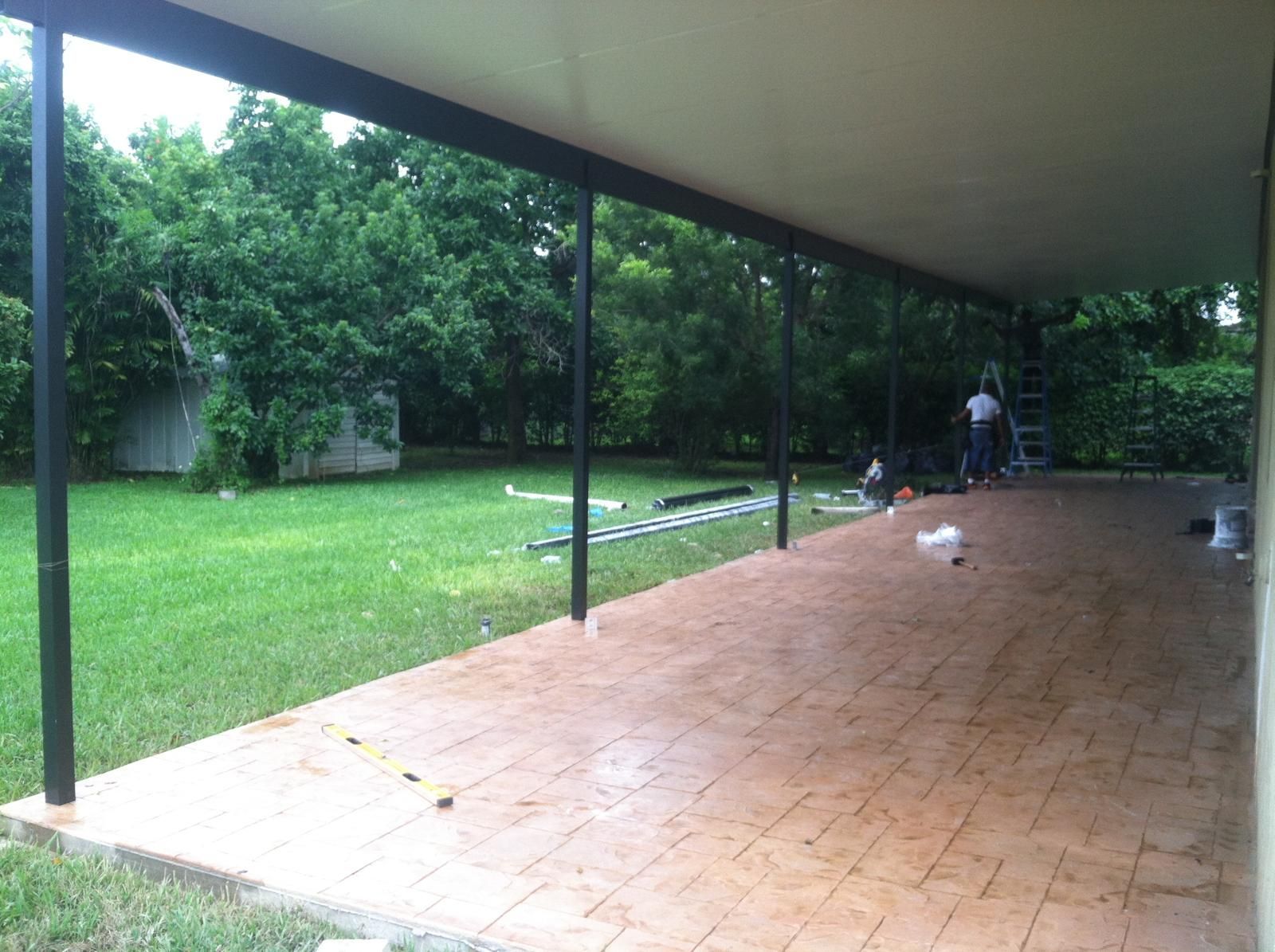 A man is working on a covered patio in a backyard.