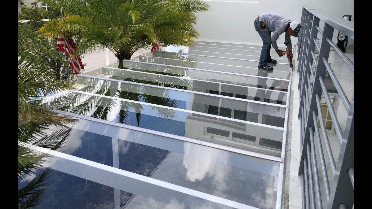 A man is working on a glass roof.