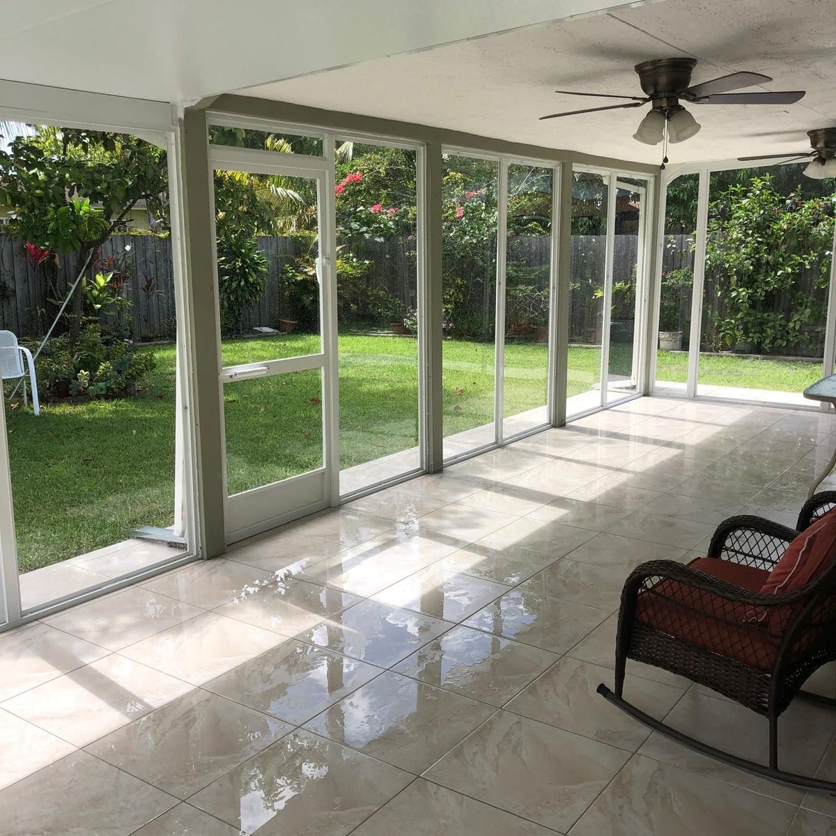 A sunroom with a rocking chair and a ceiling fan