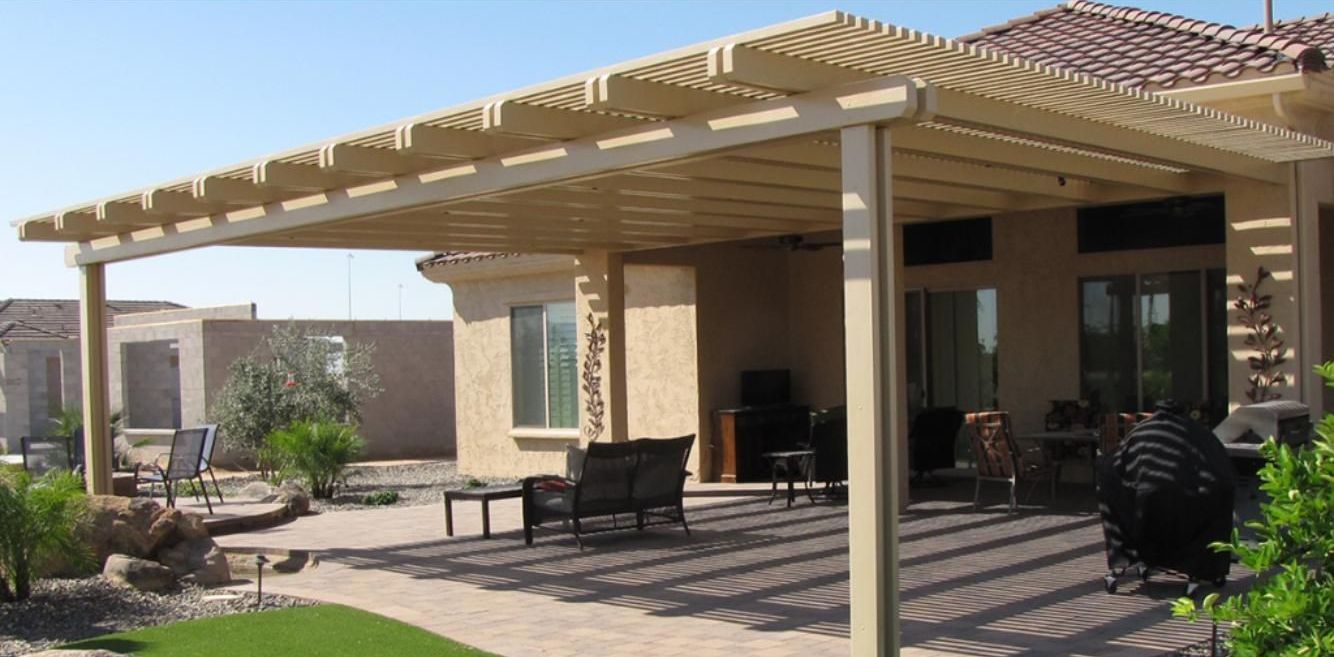 A house with a pergola and patio furniture in front of it