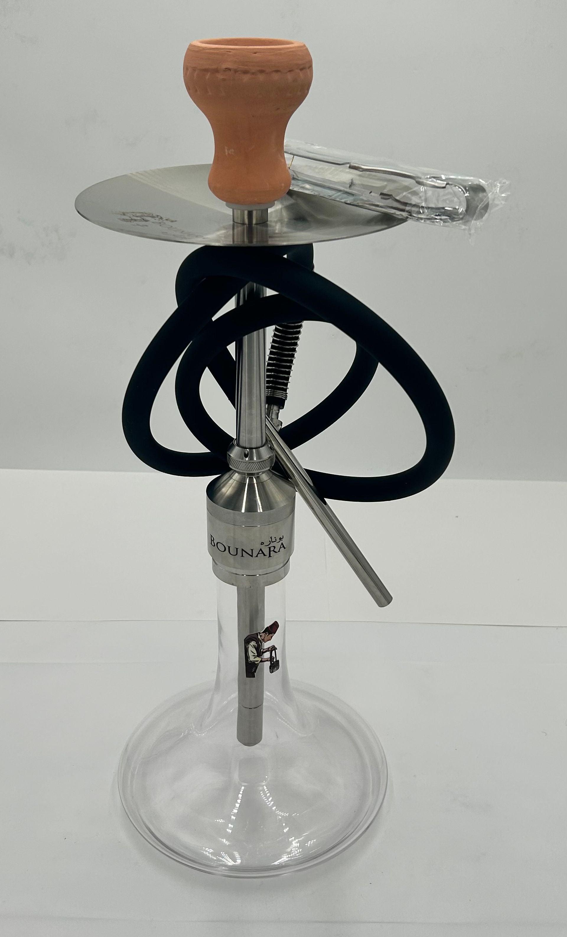 Glass hookah with a wooden top, black hose, and metal stem on a white surface