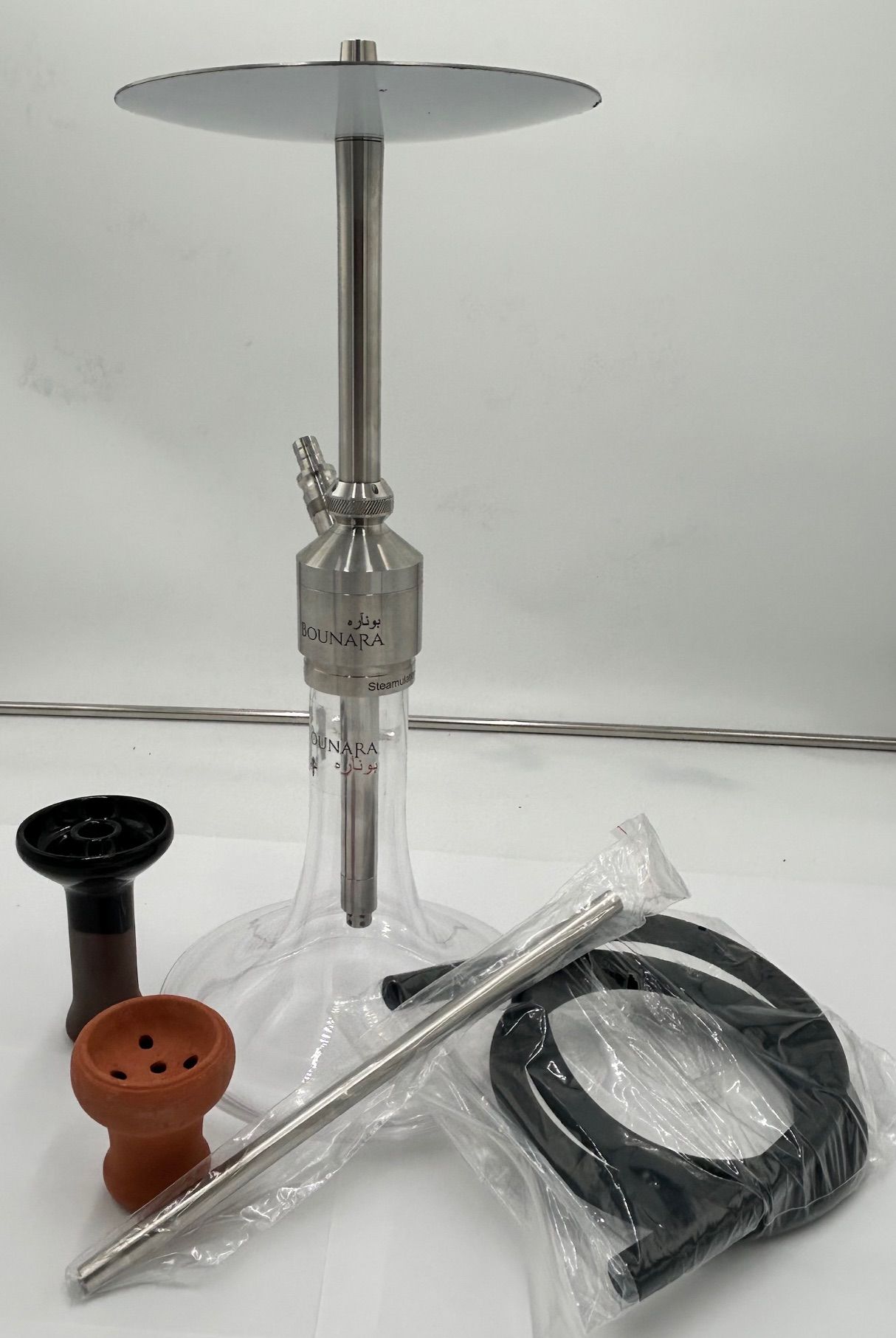 Glass hookah with a wooden top, black hose, and metal stem on a white surface