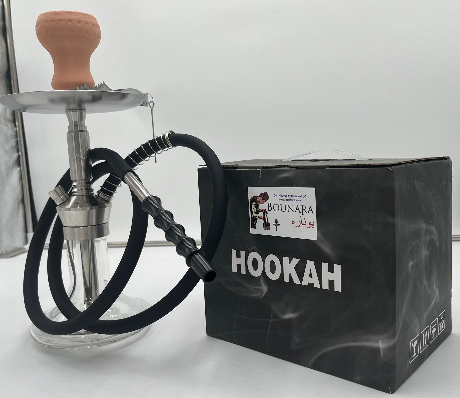 Glass hookah with a wood stem, metal tray, and black hose on a white surface