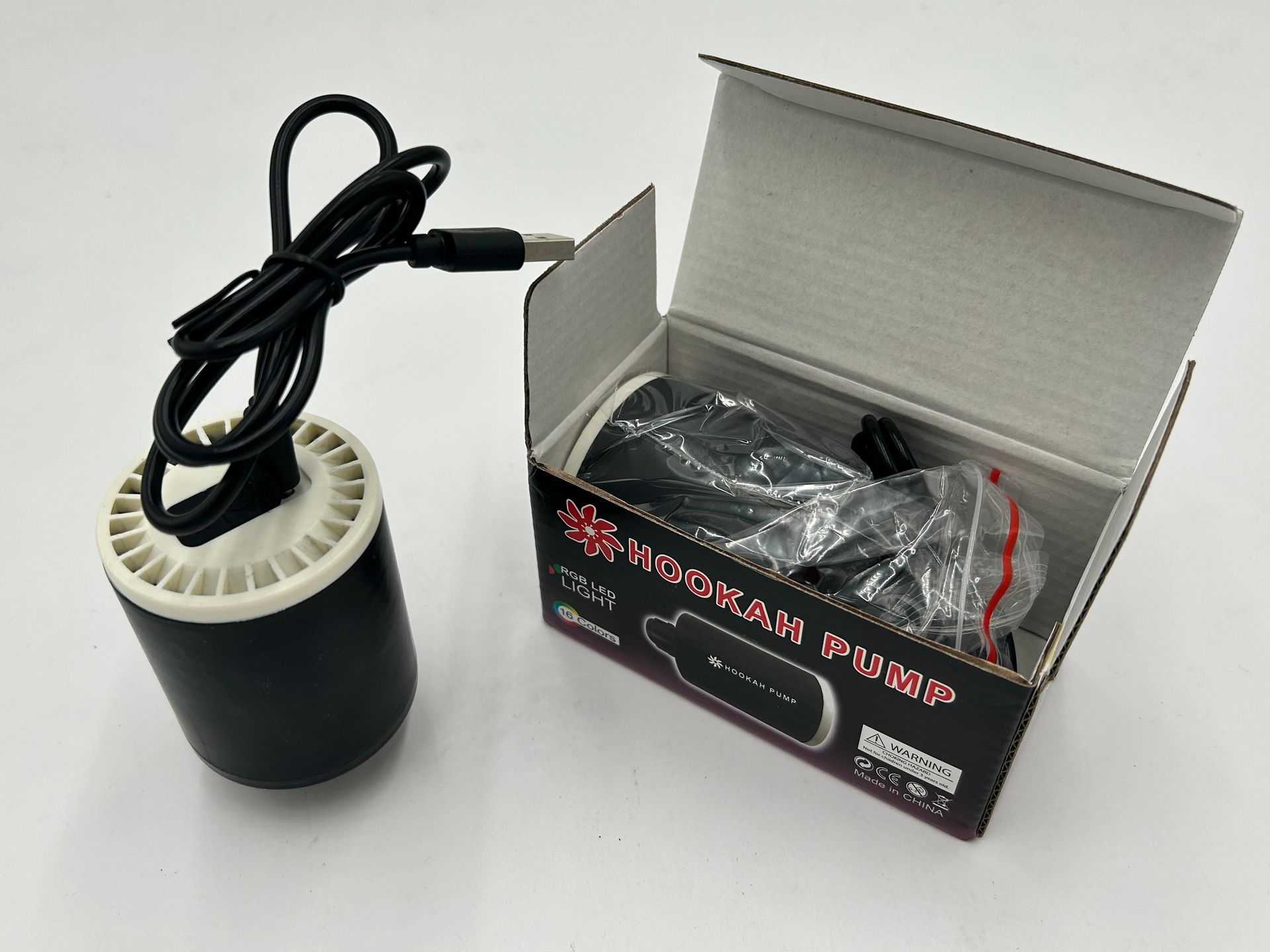Black hookah pump with USB cable next to its packaging. The box reads "Hookan Pump."
