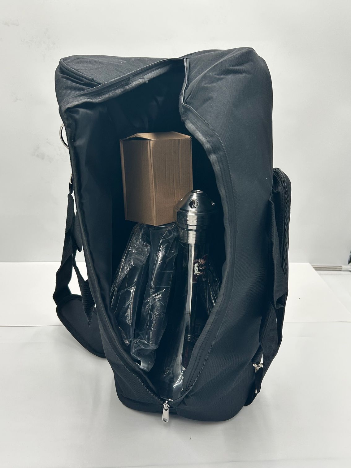 Black bag open, revealing brown box and wrapped object.