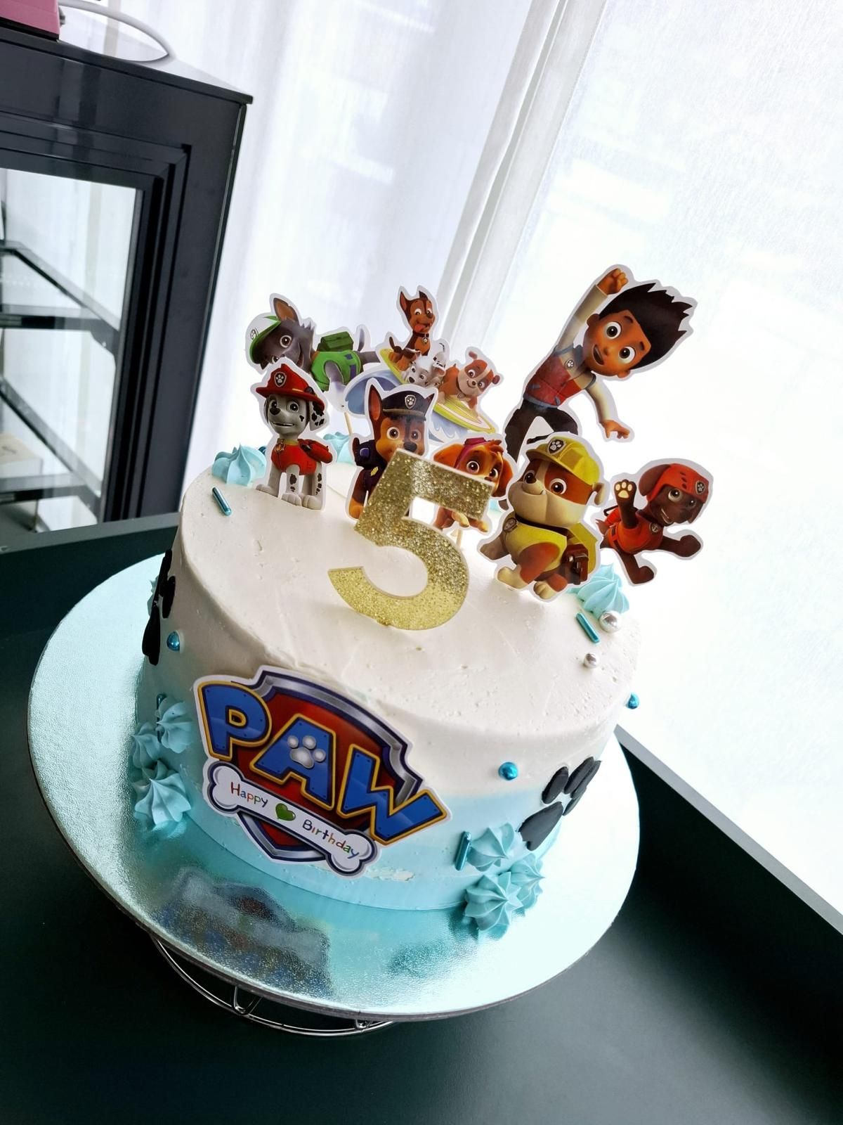 Paw-Patrol-Geburtstagstorte mit Figuren und einer goldenen „5“ obendrauf. Blau und weiß.