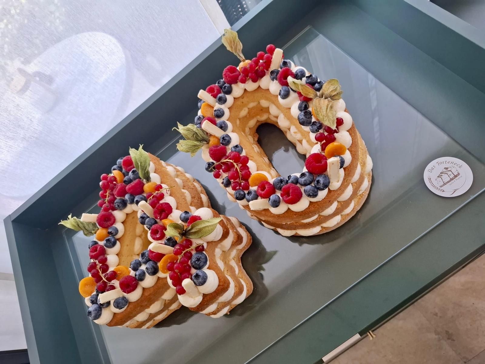 Eine mit Beeren und Sahne verzierte „40er“-Torte auf einem Tablett.