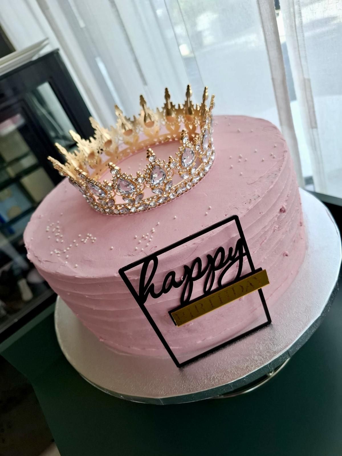 Rosa Geburtstagstorte mit goldener Krone und „Happy“-Schild.