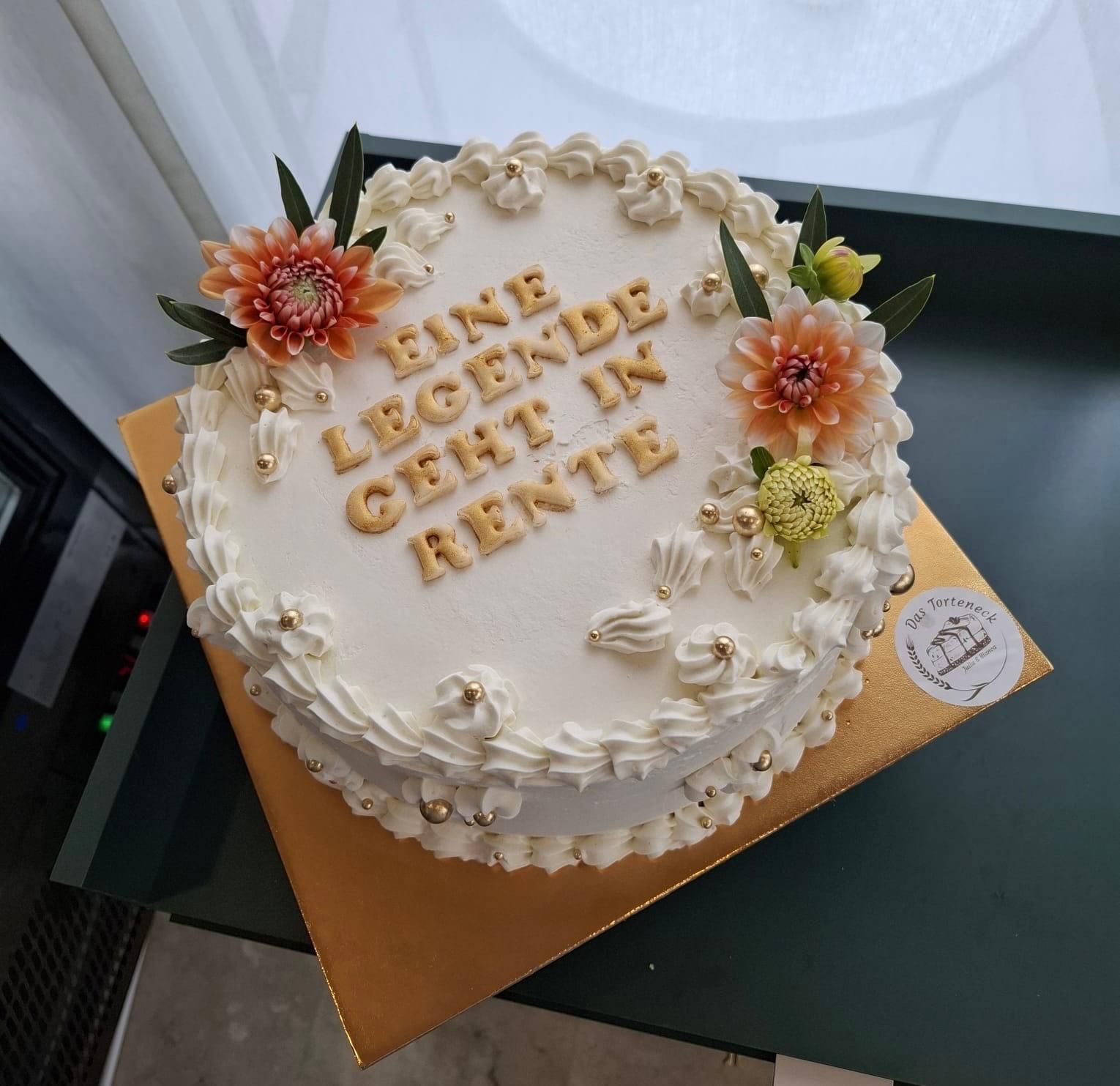 Cake with buttercream frosting and floral decorations, gold text 