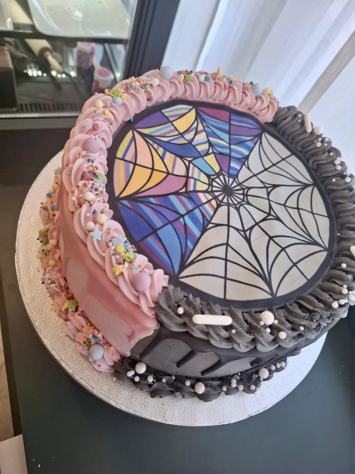 Zweifarbiger Kuchen: Seiten rosa und schwarz, Oberseite mit einem Buntglas-Spinnennetzmuster, verziert mit Zuckerguss