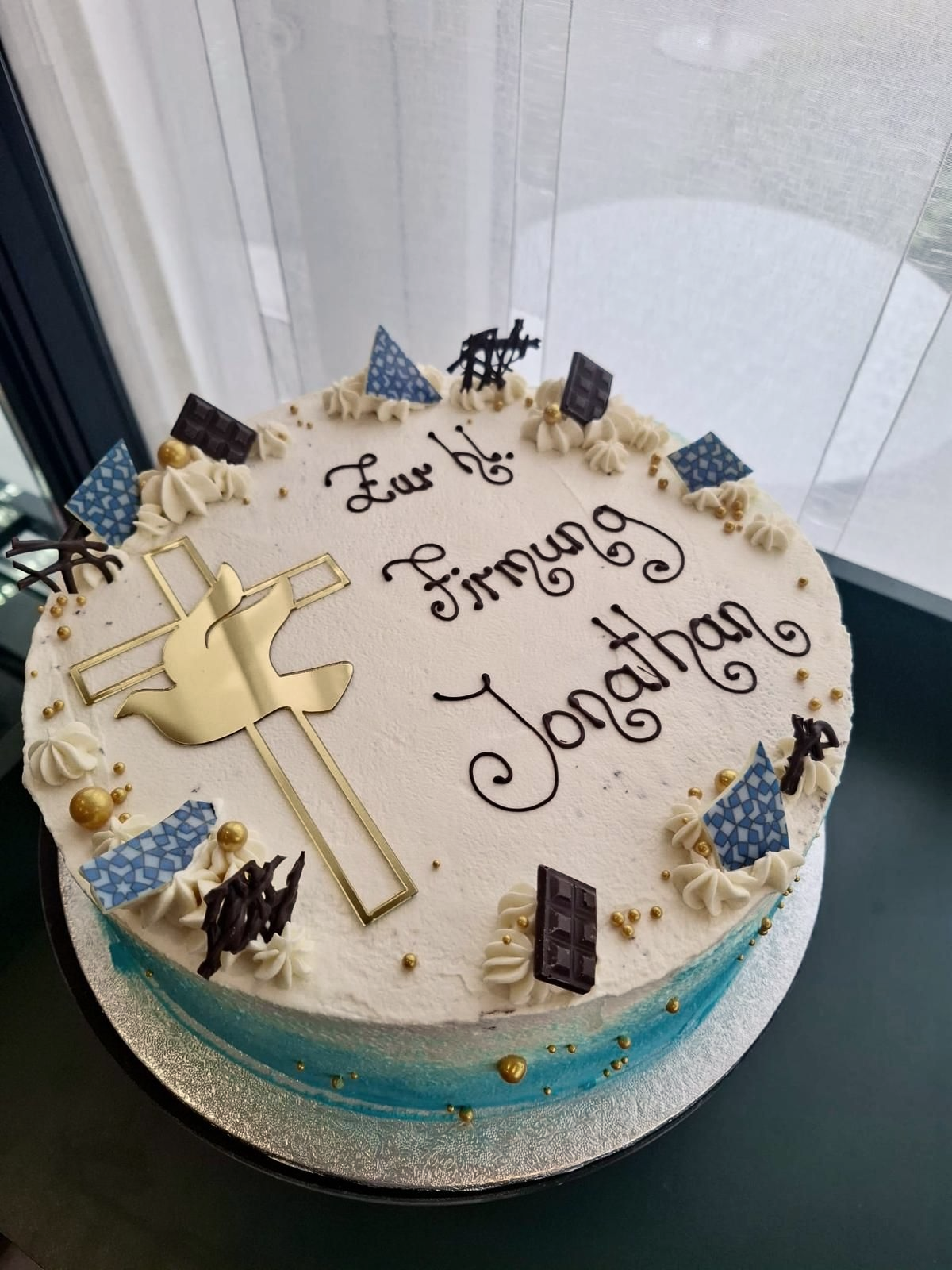 Torte zur Konfirmation verziert mit der Aufschrift „Zur hl. Firmung“, einer goldenen Taube und blauen Akzenten.