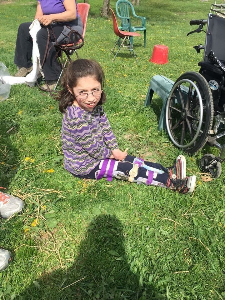 photo: young girl sitting in the grass with leg braces