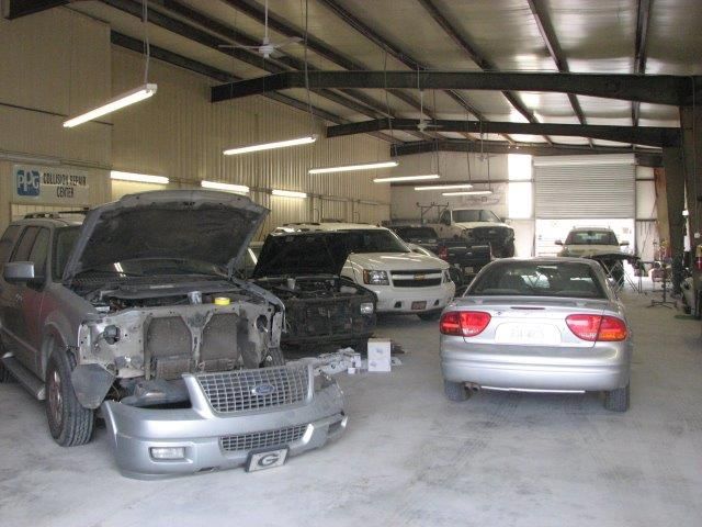 Several cars are in a garage with the hood open