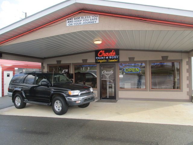 A black suv is parked in front of a store that is open