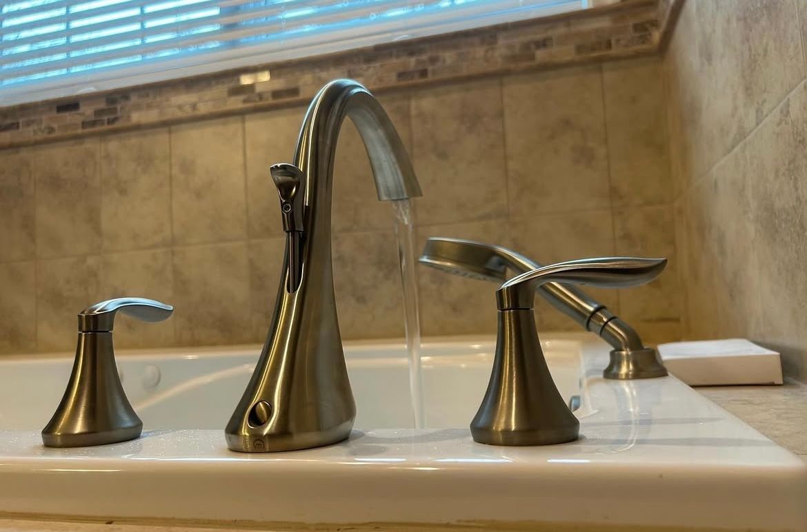 Bathroom faucet with water flowing, set against tiled wall.