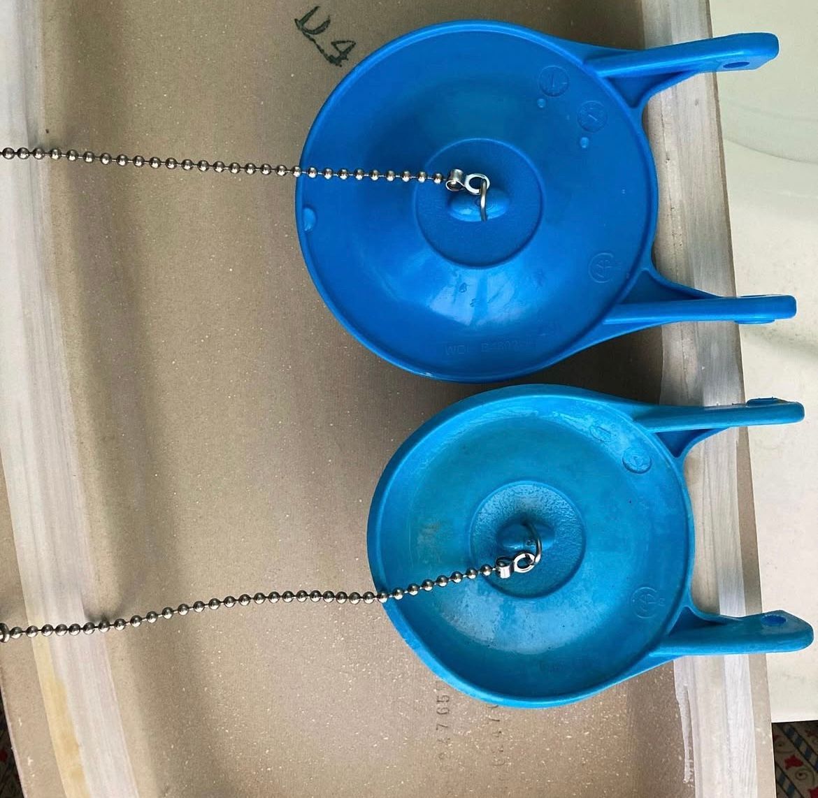 Two blue toilet flappers with metal chains.