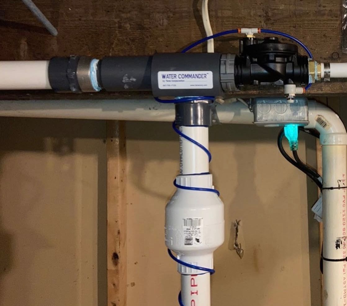 Plumbing system with a water conditioner and various pipes attached to a wooden wall.