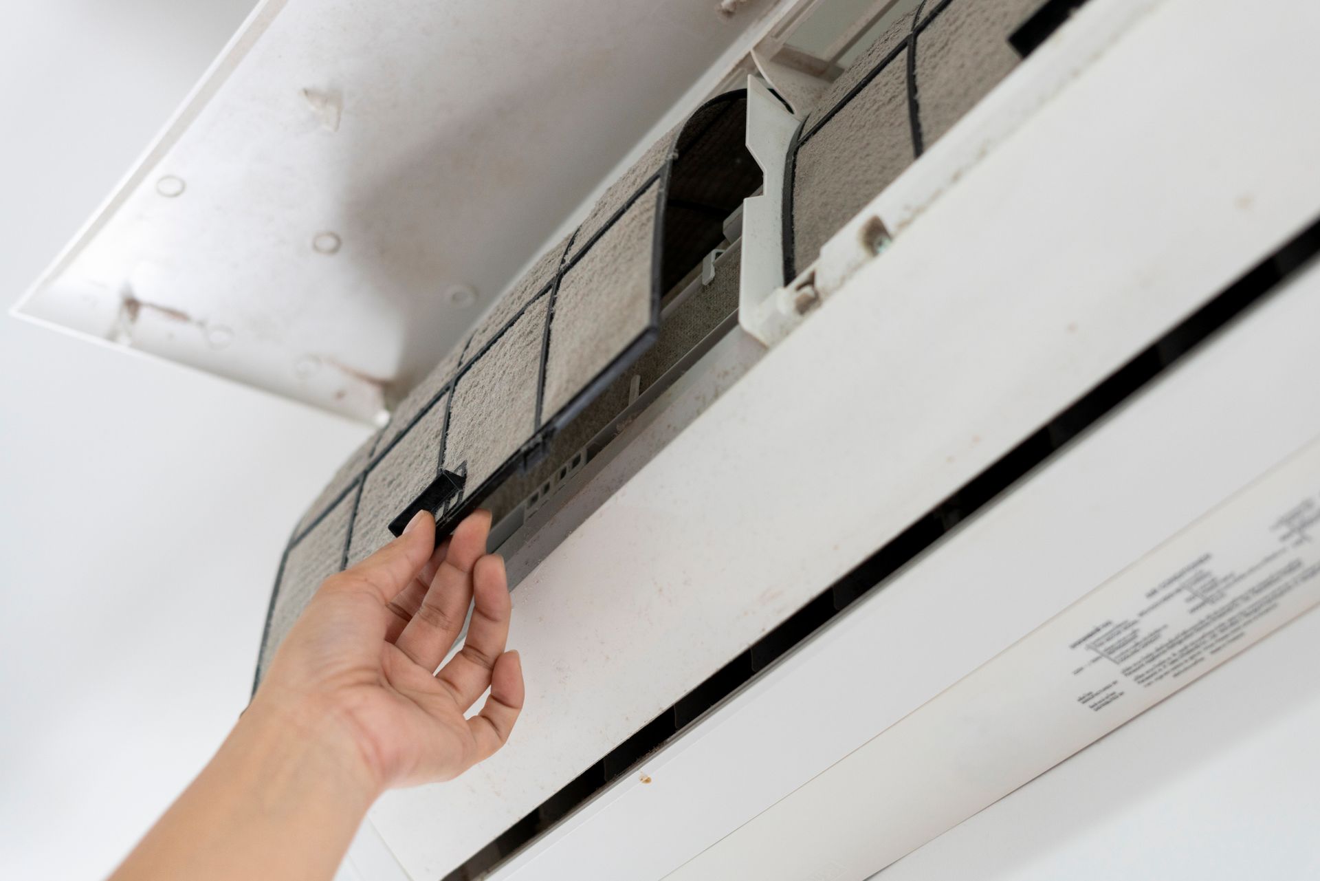 A living room with a white couch and a thermostat on the wall.