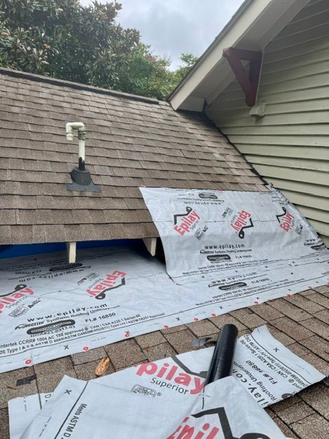Roof repair in progress with underlayment exposed and shingles removed near a dormer vent.