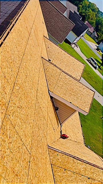 Sloped shingle roof with several dormers beside a green suburban lawn under clear daylight