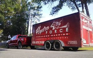 A red truck is parked next to a red trailer.