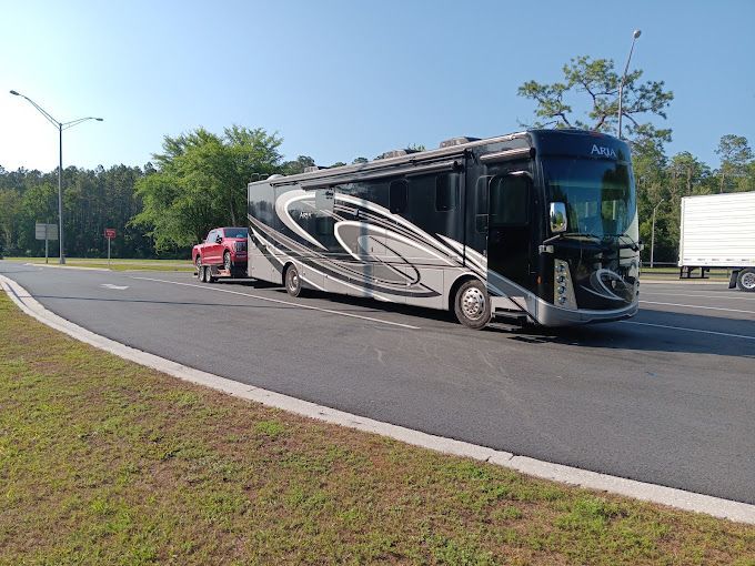 A large rv is towing a smaller rv down a road.