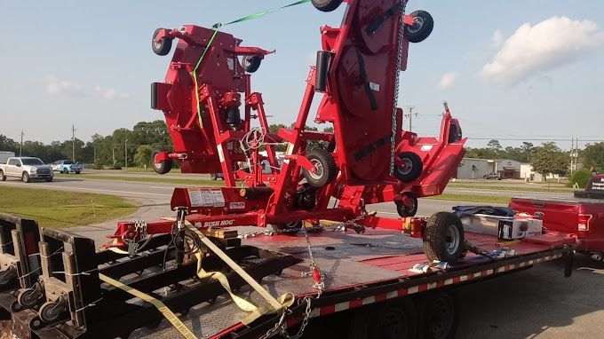 Two red tractors are sitting on top of a trailer.