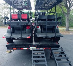 Two golf carts are parked on a trailer with ramps