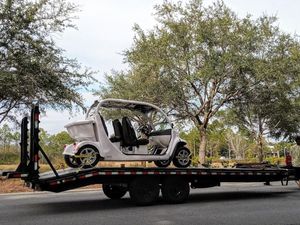 A golf cart is being towed on a trailer.