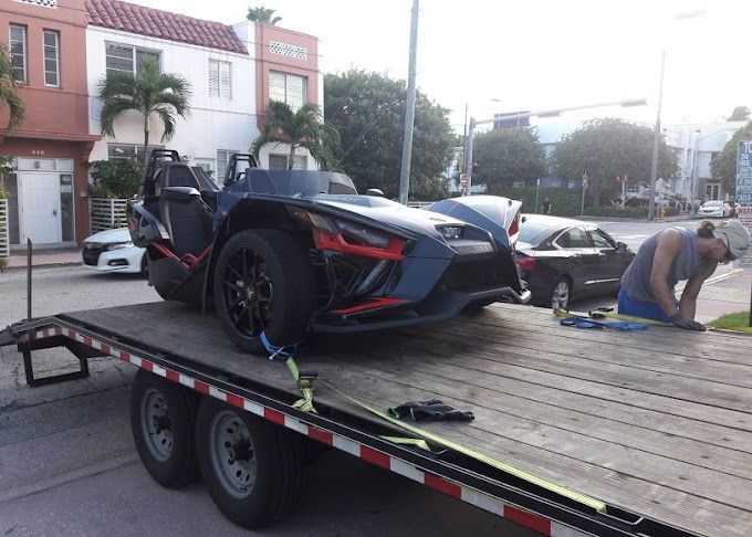 A man is working on a trailer with a slingshot on it.