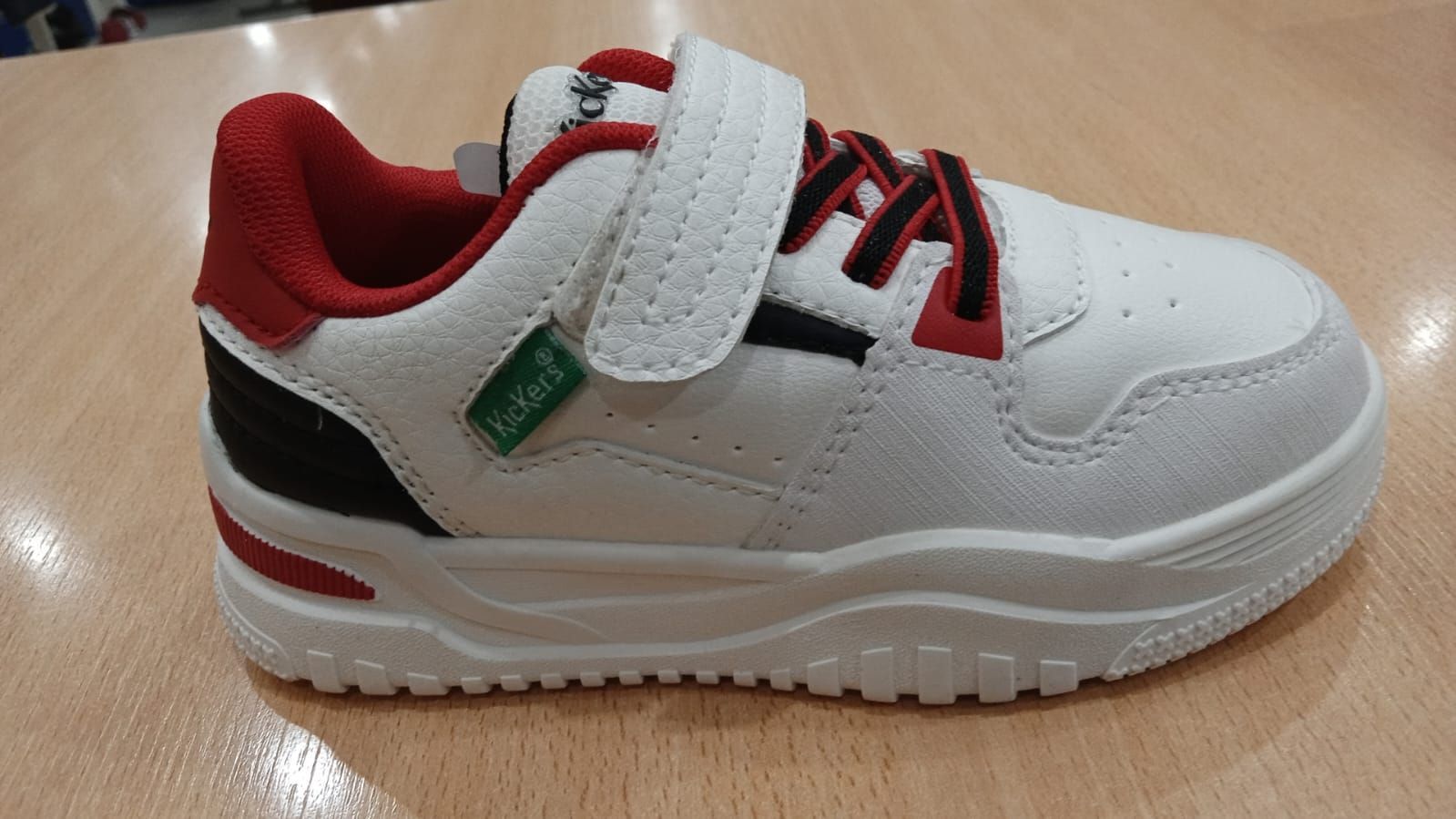 Zapatilla infantil de color blanco y rojo con tira de velcro.