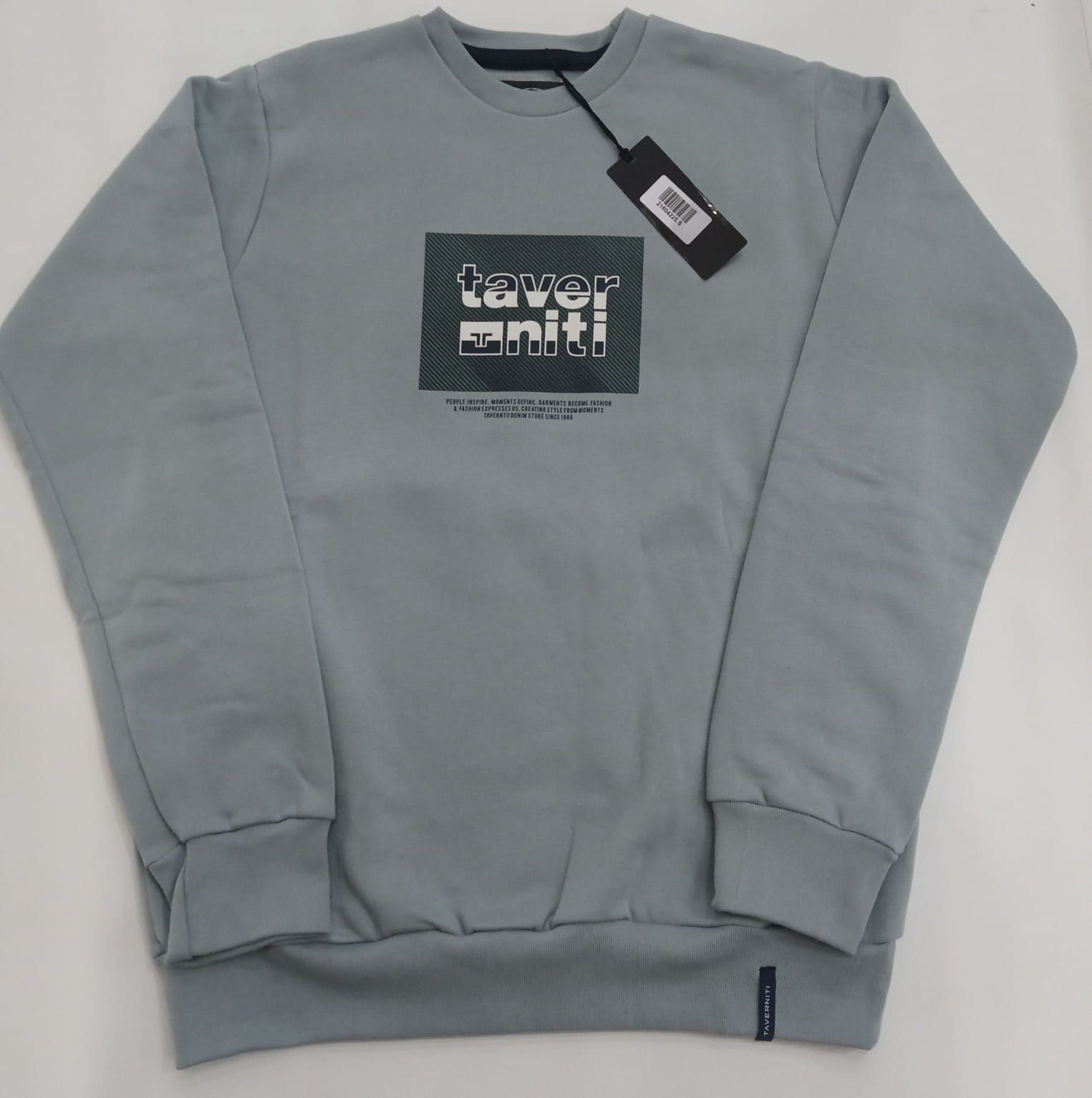 Sudadera gris claro de cuello redondo con un pequeño gráfico en el pecho y etiqueta colgante sobre fondo blanco.