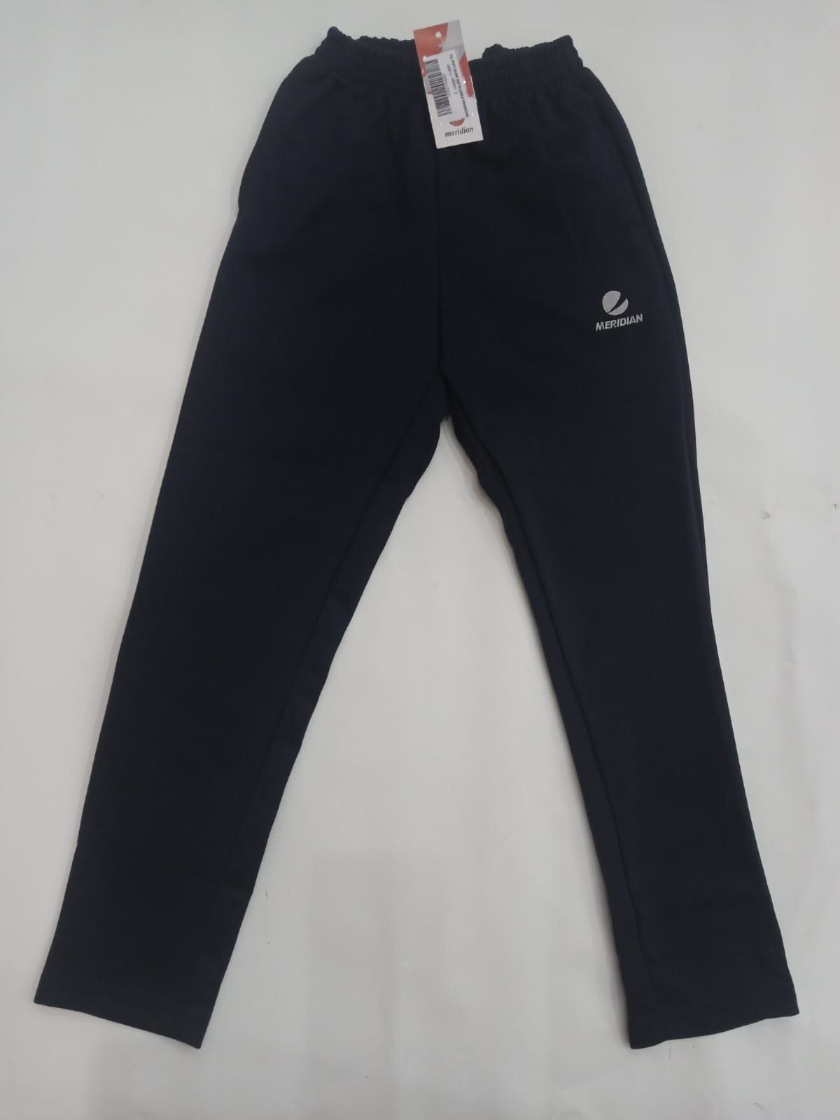 Pantalones deportivos negros extendidos sobre un fondo blanco con una etiqueta en la cintura.