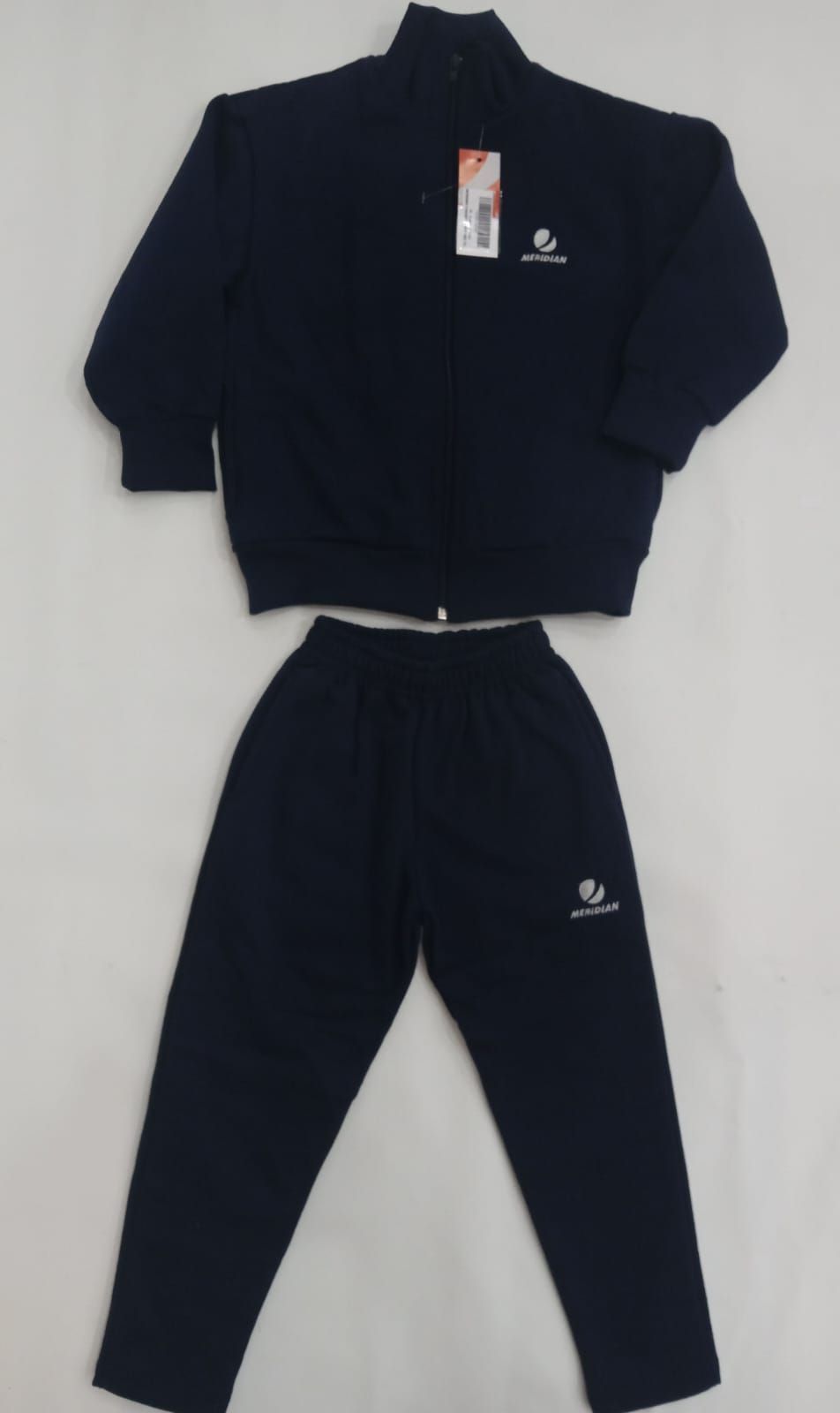 Conjunto de chándal negro con chaqueta y pantalón con cremallera, extendido sobre un fondo blanco.