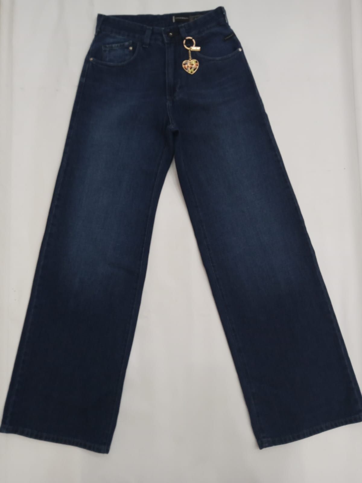 Pantalones vaqueros anchos de color azul oscuro con un detalle de llavero dorado en la cintura.