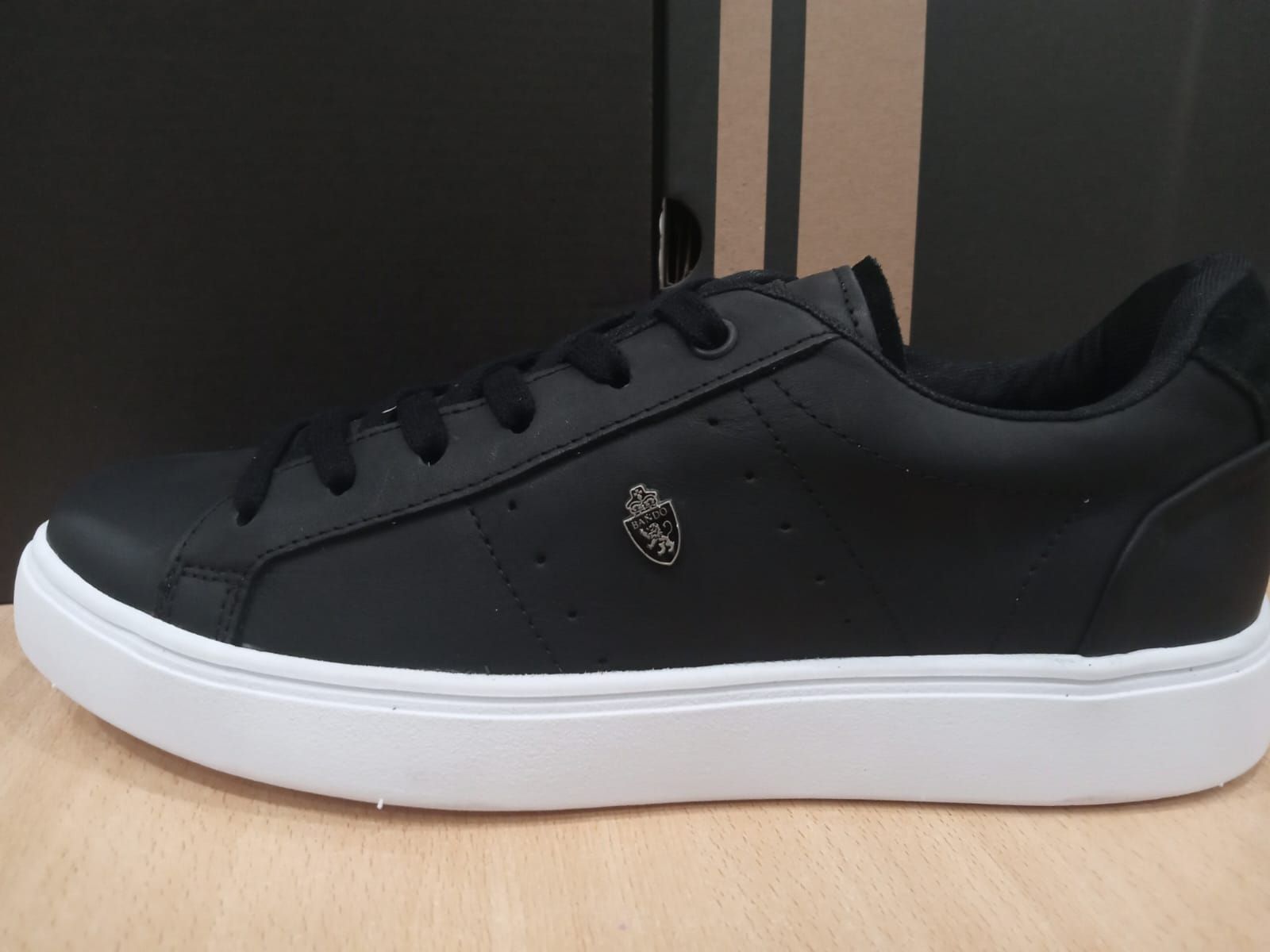 Zapatillas bajas negras con suela blanca, mostradas de perfil sobre un fondo liso.