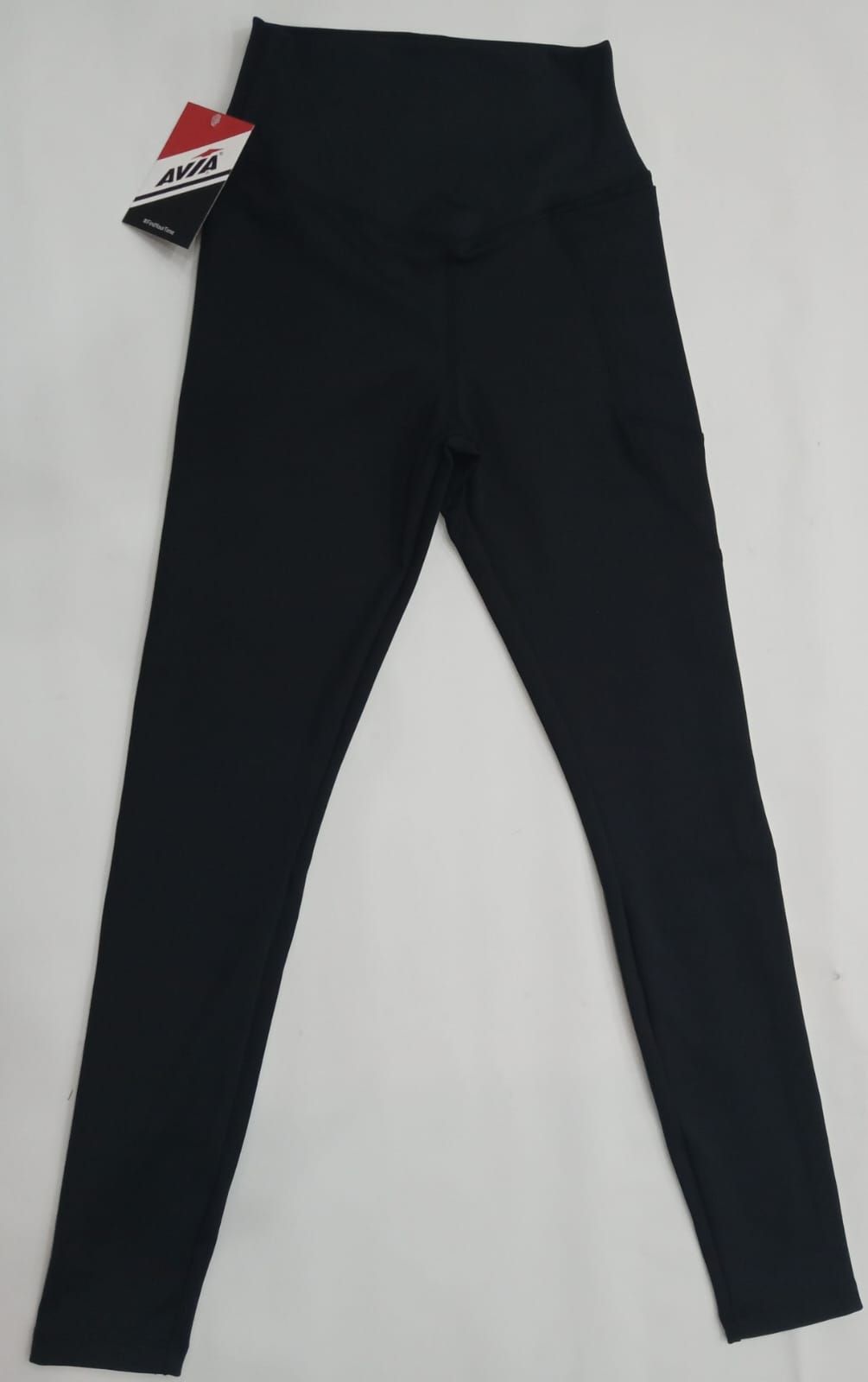 Leggings negros con etiqueta, extendidos sobre un fondo blanco.