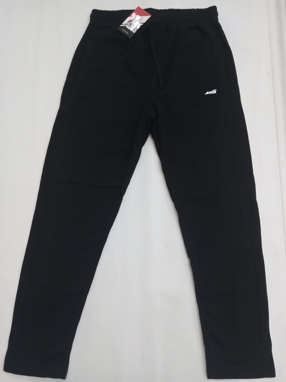 Pantalones deportivos negros con un pequeño logotipo blanco, colocados sobre un fondo blanco.