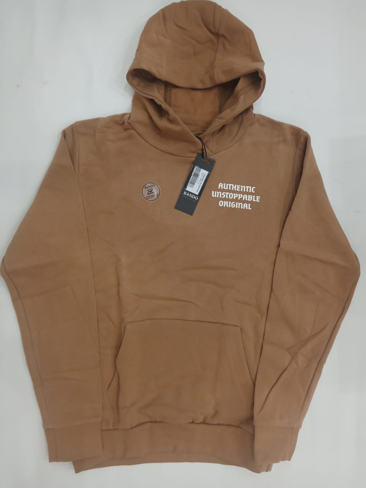 Sudadera marrón con capucha, extendida sobre una superficie plana, con un pequeño gráfico en el pecho y una etiqueta adjunta.