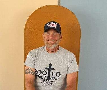 Man wearing a black hat and grey t-shirt that says 