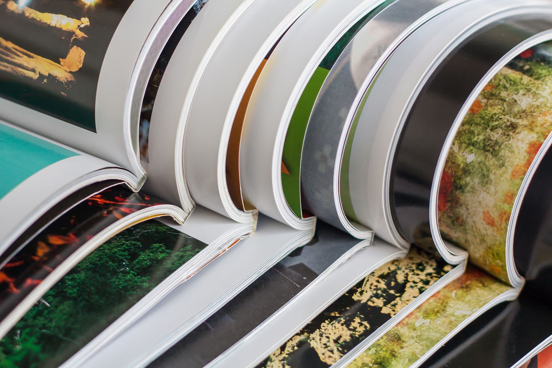Close-up of a magazine’s pages fanning out, showing colorful, diverse images on each paper sheet.