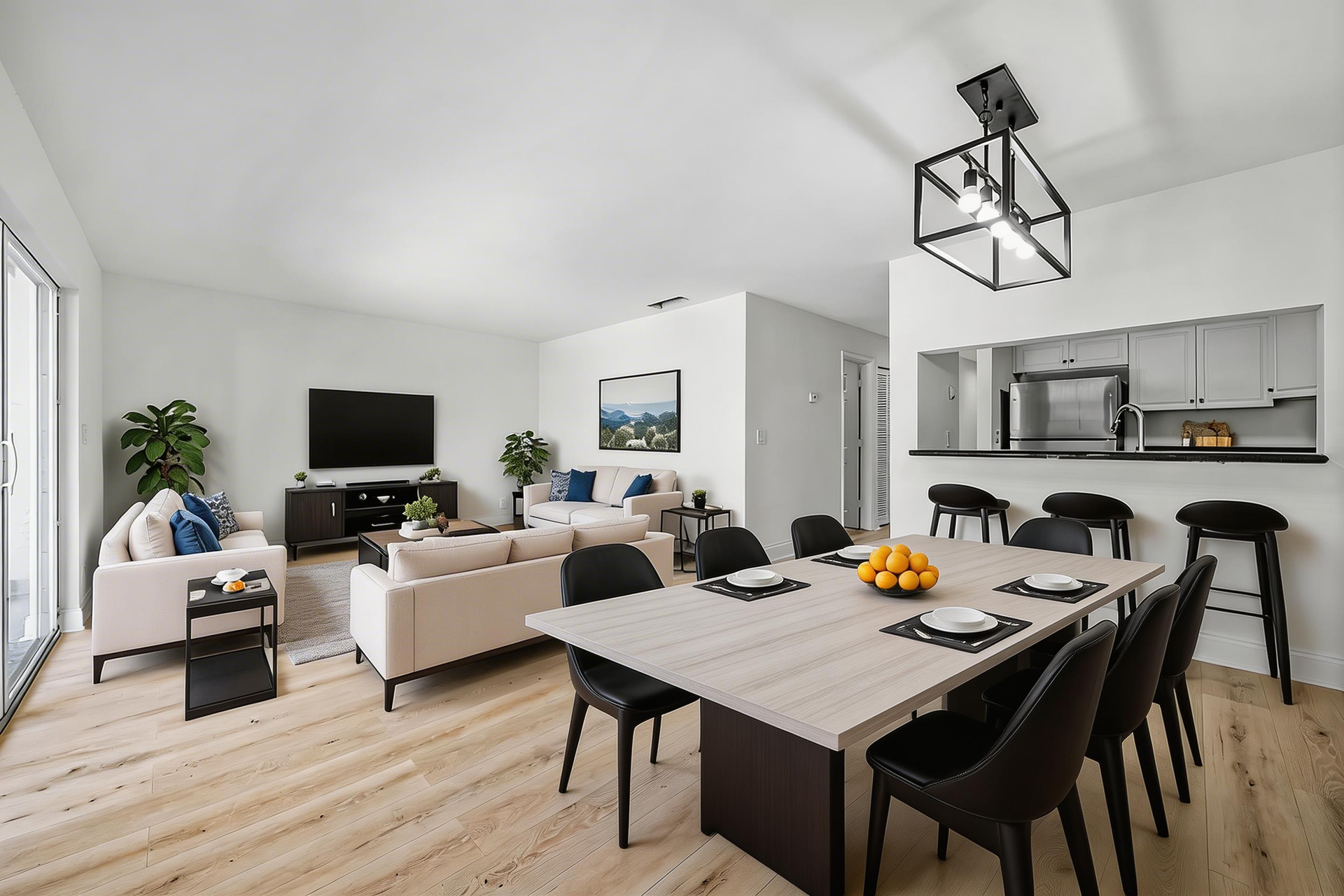 Open-concept home interior featuring a dining area with a modern light fixture, living room with sofas, and a kitchen bar.