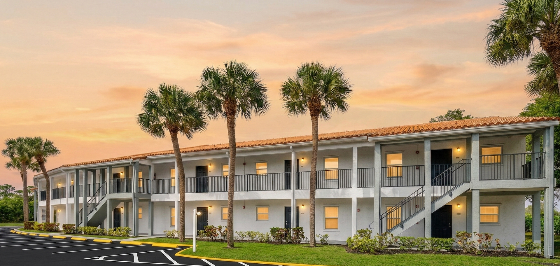 A bright, open-plan dining area with a round table, four chairs on a rug, and a bedroom doorway visible in the background.