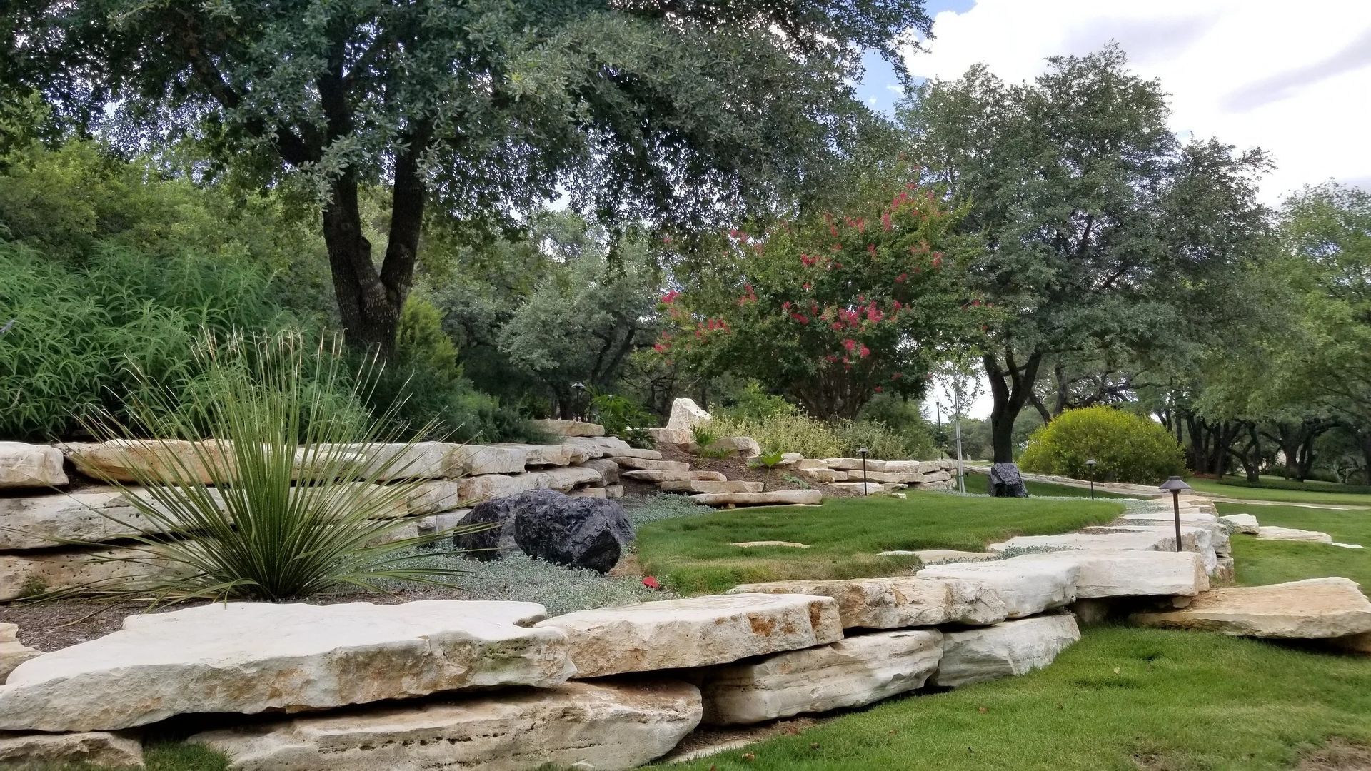 Stone retaining walls in a garden with trees and greenery.